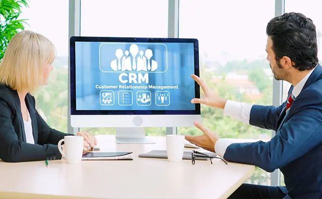 CRM office discussion: Woman and man analyze customer relationship management software.
