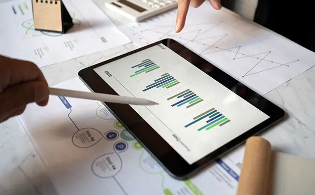 Data analysis meeting: Tablet displays charts for fintech strategy planning.