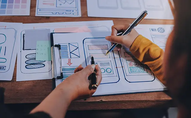 UI/UX design sketches on a wooden table illustrate mobile app development for emerging markets.